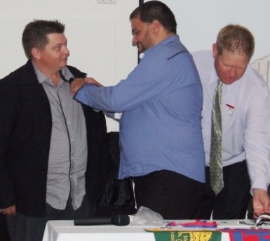 Mark Gauci gets his Life Member badge pinned on by Sandro Capocchi, with Darren Nagle lurking behind.