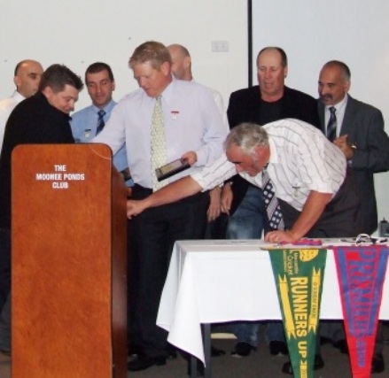 Prez Charlie Walker reaches into the lectern for the Life Member medallion. On stage are Life Members (from left) John Talone, Mark Gauci, Jim Polonidis, Darren Nagle, Michael Harvey, Ian Denny and Joe Ansaldo.