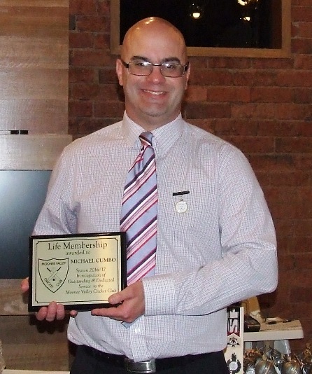 Michael Cumbo proudly wears his Life Member badge and holds the memento plaque celebrating his honor.