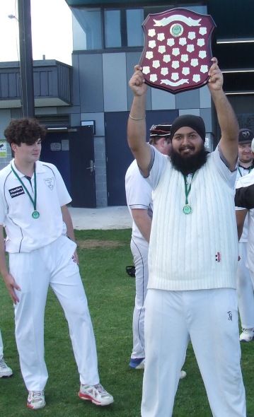 Tom Morrissy looks on as Manu Singh holds the Premiership shield aloft.