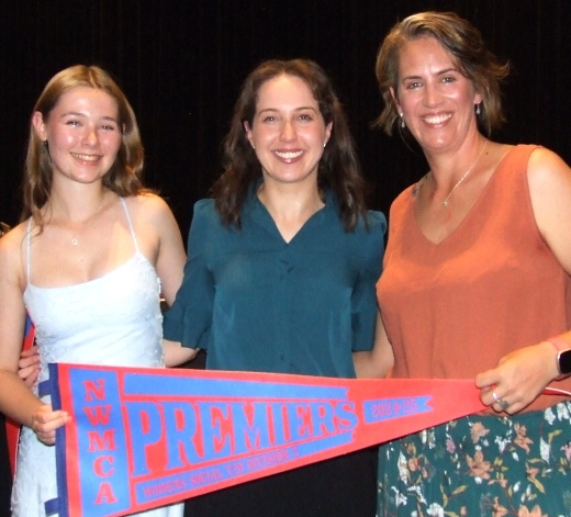 L-R Katherine Baker and Sarah Fenn receive the Premiership flag from NWMCA Women's Committee member Jayde Lee.