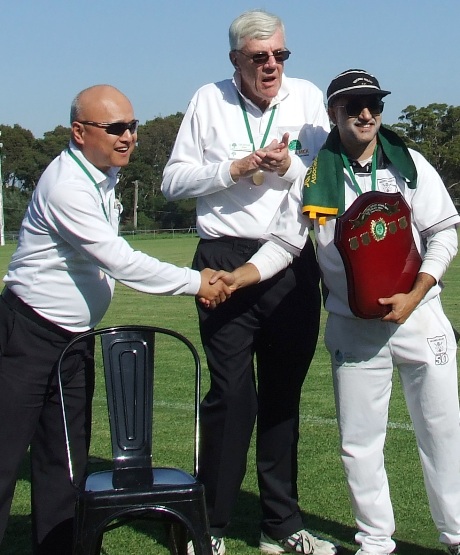 Captain Sunny Sharma receives the premiership shield and flag from umpires Wilson Chan (left) and Graham Slater.
